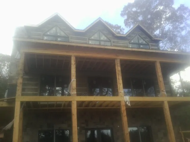 Dormers and porch framing on a large log home under construction — Roof Coating work by our crew in Crowley