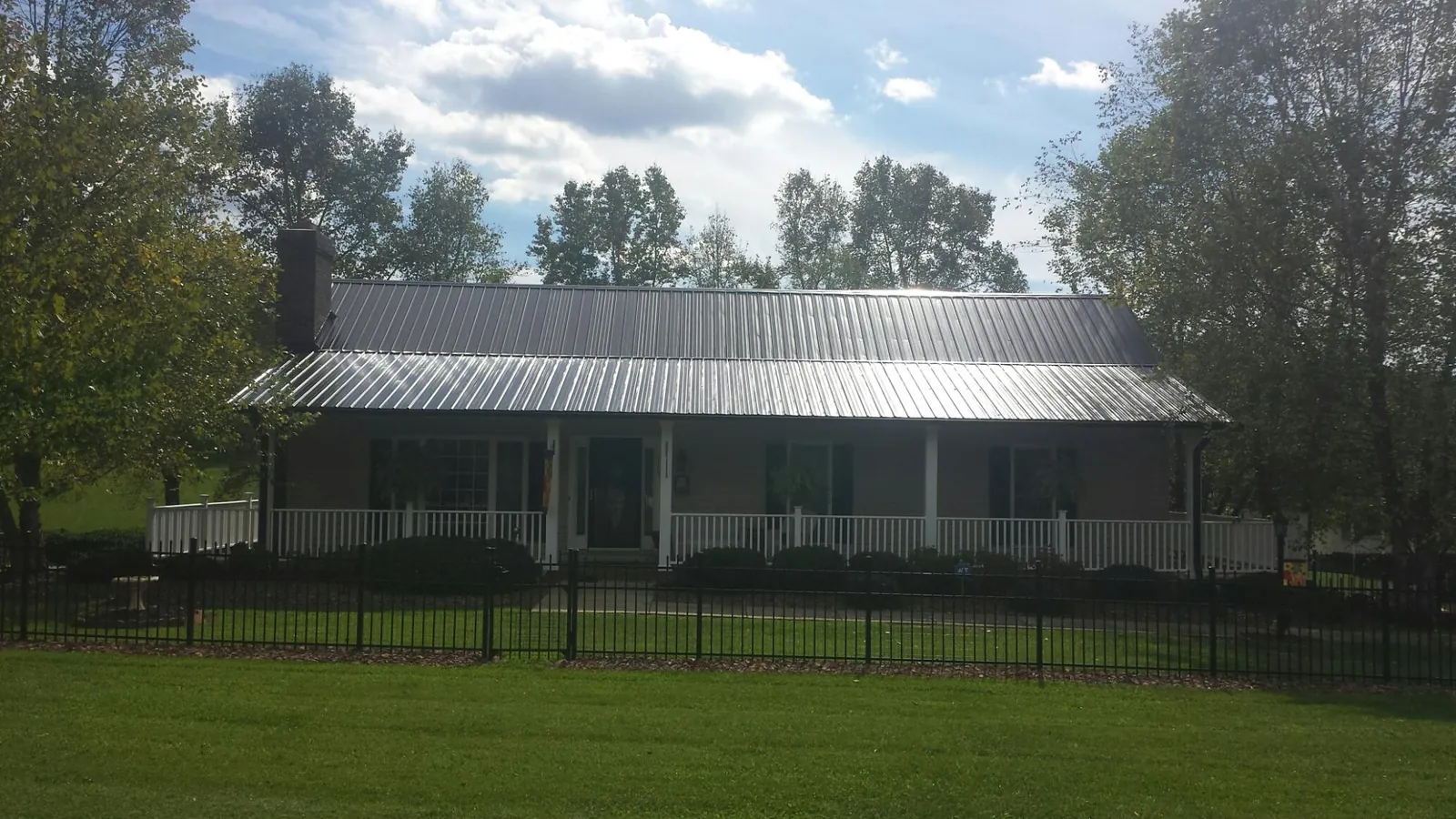 Gray metal roof on a brick ranch with a full width front porch — Gutter Guard Installation work by our crew in Crowley