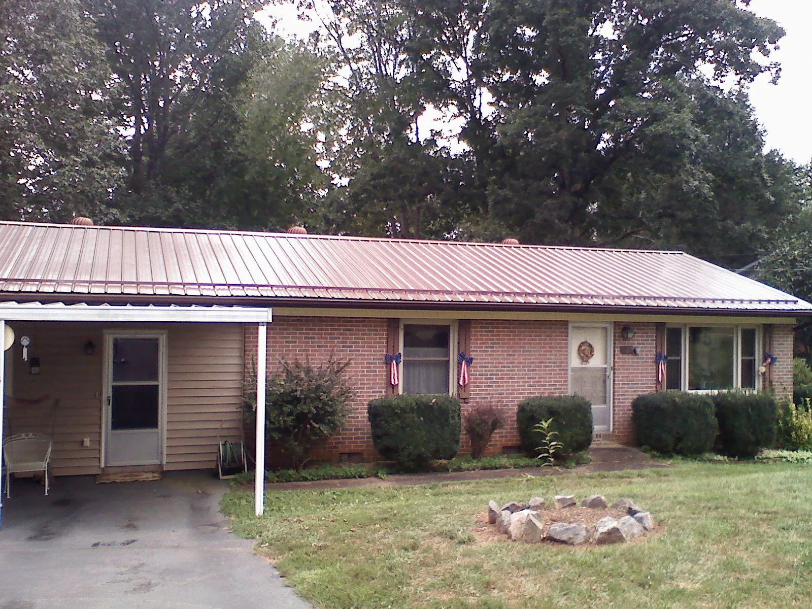 Bronze metal roof and carport on a brick ranch home — Roof Repair work by our crew in Crowley